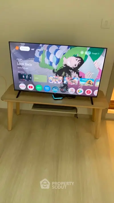 Modern living room with sleek TV setup on wooden stand, showcasing a cozy and stylish interior.