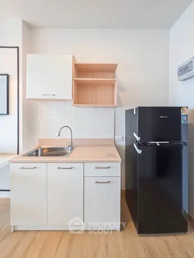 Modern kitchen with sleek cabinetry and black refrigerator in a stylish apartment.