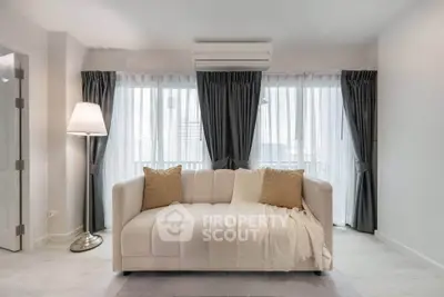 Modern living room with elegant sofa and floor lamp, featuring large windows with stylish curtains.