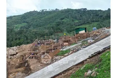 Scenic hillside construction site with lush greenery and developing infrastructure.