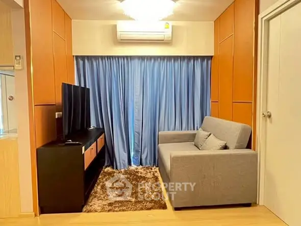 Cozy living room with modern sofa, TV, and air conditioning, perfect for relaxation.