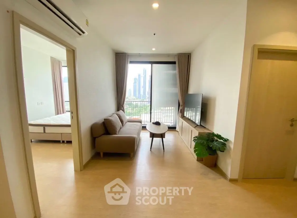 Modern living room with city view, featuring a cozy sofa, TV, and large windows for natural light.