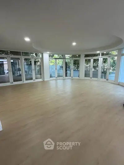Spacious circular room with large windows and wooden flooring, ideal for modern living.