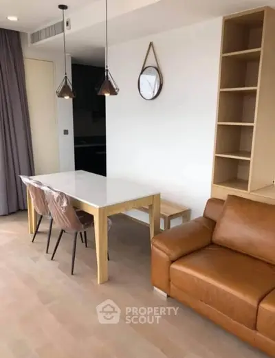 Modern living room with leather sofa, dining table, and stylish decor in a bright apartment.