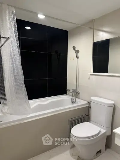 Modern bathroom with sleek black and white design featuring a bathtub and shower combo.