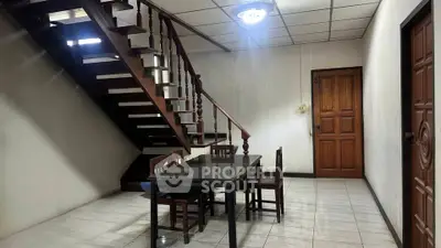 Spacious dining area with wooden staircase and modern lighting in a cozy home.