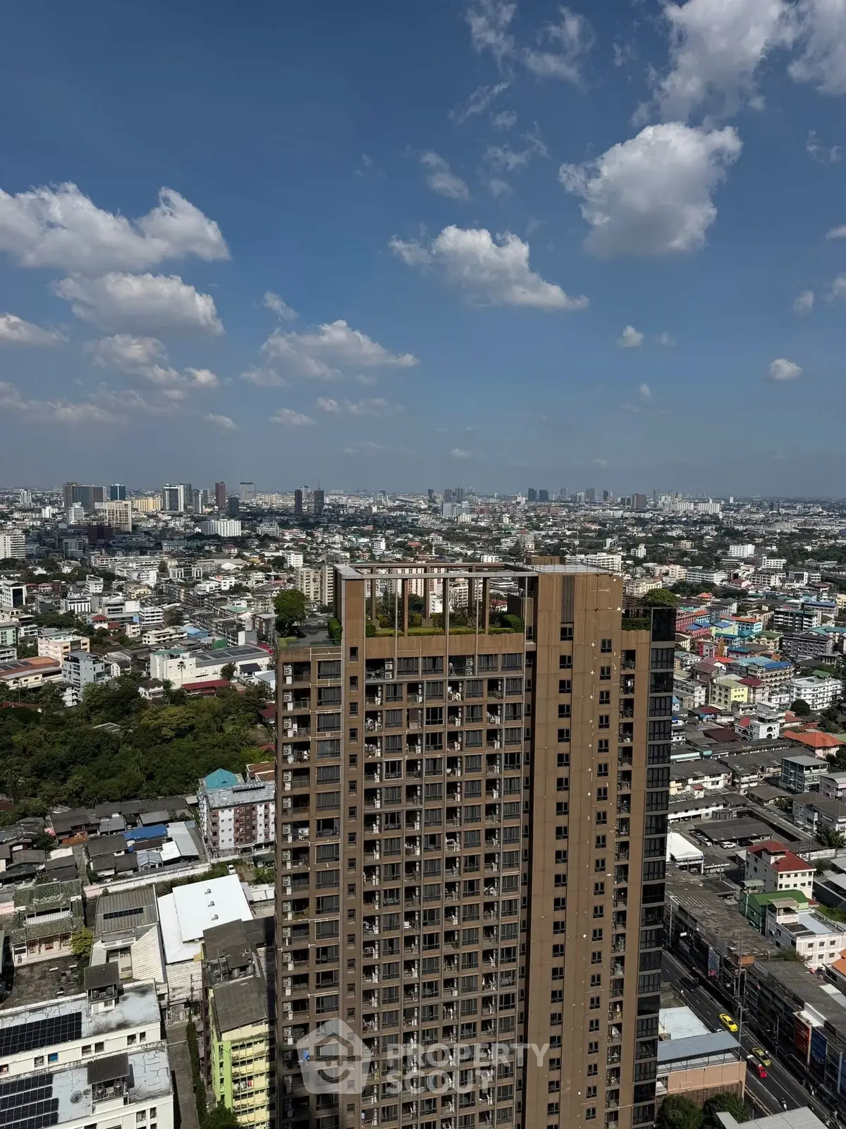 Stunning aerial view of a modern high-rise building with a panoramic cityscape backdrop under a clear blue sky.