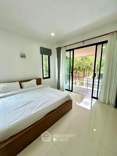 Spacious bedroom with large windows and balcony access, offering serene garden views.