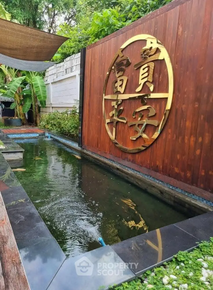 Serene garden pond with elegant wooden wall and lush greenery