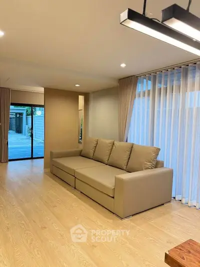 Modern living room with beige sofa and large windows for natural light.