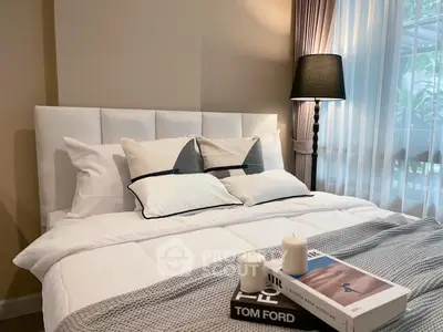 Cozy bedroom with elegant decor, featuring a plush bed, stylish lamp, and serene window view.