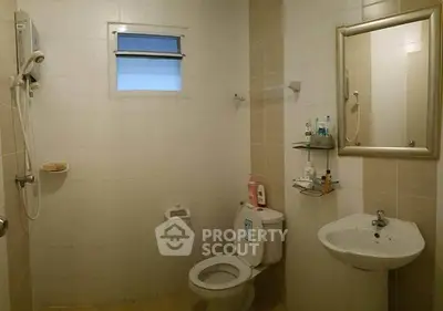 Spacious bathroom with modern fixtures and neutral tiles, featuring a shower and vanity mirror.