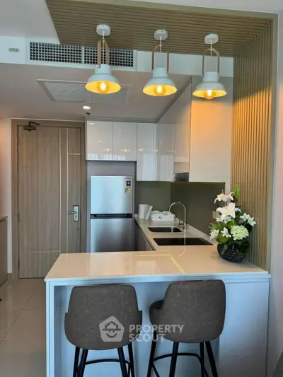 Modern kitchen with sleek design, featuring a breakfast bar, stylish lighting, and stainless steel appliances.