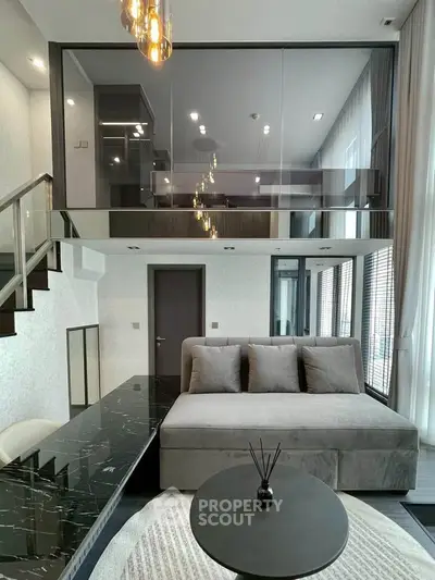 Modern duplex living room with sleek design and glass mezzanine, featuring stylish furniture and elegant lighting.