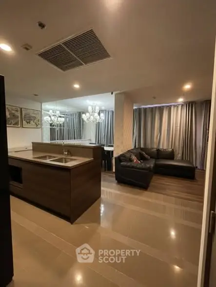 Modern open-layout kitchen and living room with elegant lighting and stylish furnishings.