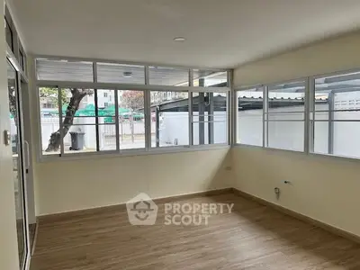 Spacious and sunlit living room with large windows offering an inviting atmosphere and ample natural light, perfect for relaxation or entertaining guests.