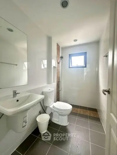 Modern bathroom with sleek fixtures and natural light, featuring a shower and contemporary design.