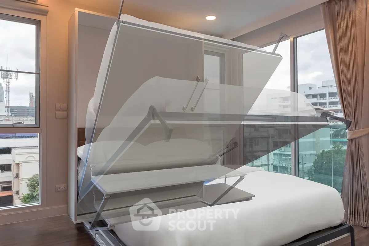 Modern bedroom with innovative foldable bed and large windows offering city views.