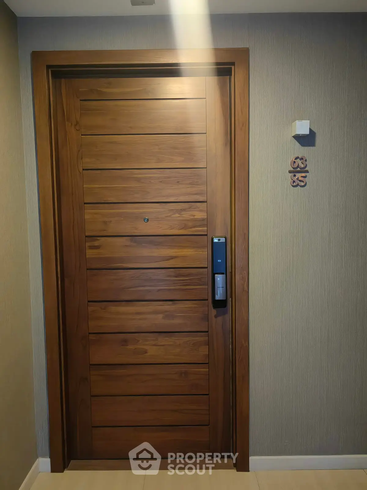 Elegant wooden apartment door with modern electronic lock in a stylish hallway.