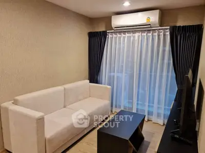 Cozy living room with modern sofa and TV, featuring elegant curtains and air conditioning.