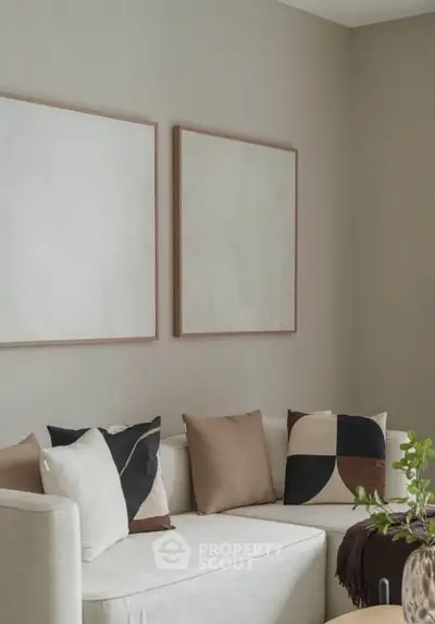 Modern living room with stylish decor and neutral tones, featuring a cozy white sofa and abstract wall art.