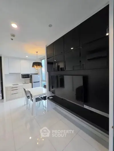 Modern open-layout kitchen and dining area with sleek black cabinetry and large TV