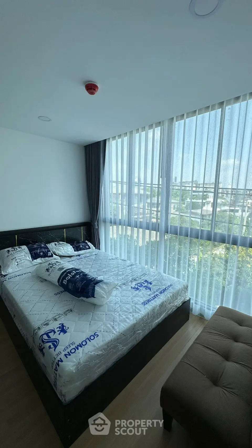 Spacious bedroom with large windows and modern furnishings in a bright apartment.