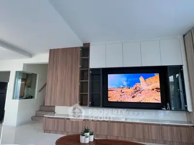 Modern living room with sleek wooden cabinetry and large TV display
