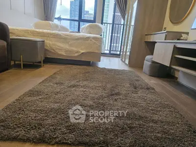 Modern bedroom with city view, featuring a cozy rug and stylish furniture, perfect for urban living.