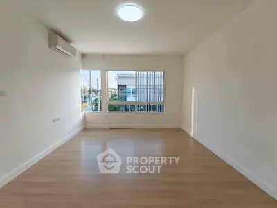 Spacious empty room with large windows and wooden flooring, perfect for customization.