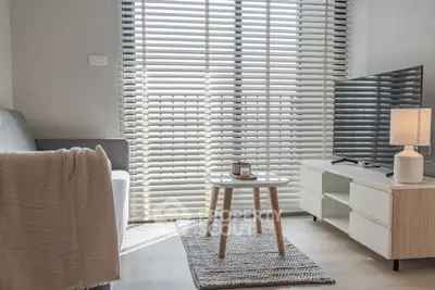 Modern living room with sleek furniture and large window blinds, creating a bright and inviting space.