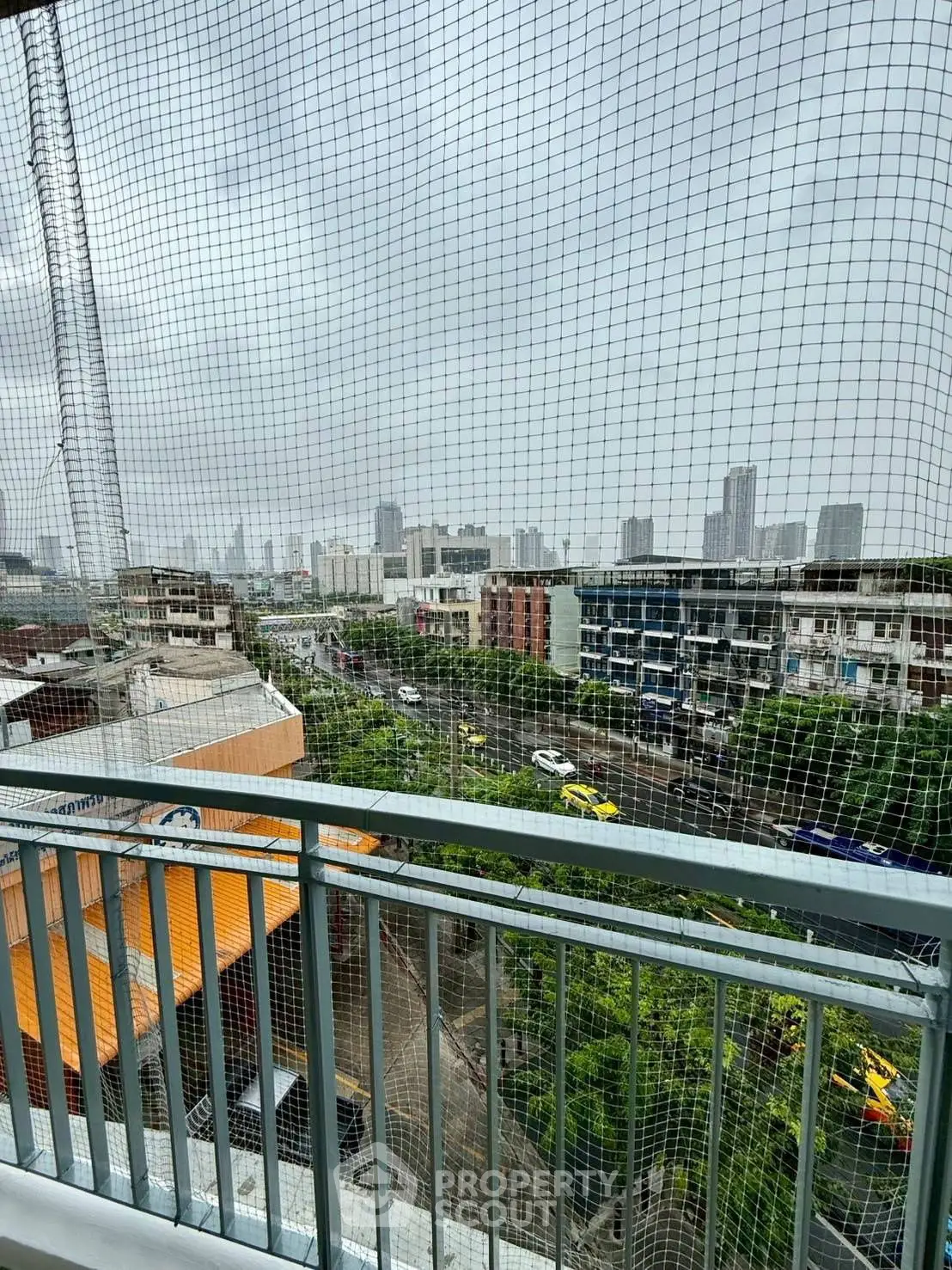 Urban balcony view with cityscape and safety netting, ideal for city living enthusiasts.