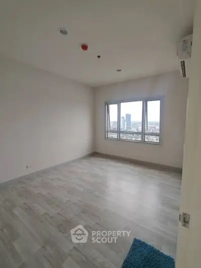 Spacious empty room with large window offering city view, perfect for customization.