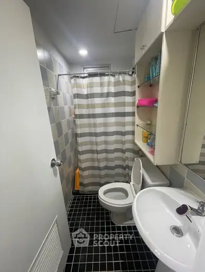 Compact bathroom with modern fixtures and striped shower curtain in a cozy apartment.