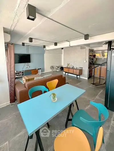 Modern industrial-style living room with colorful dining set and open layout