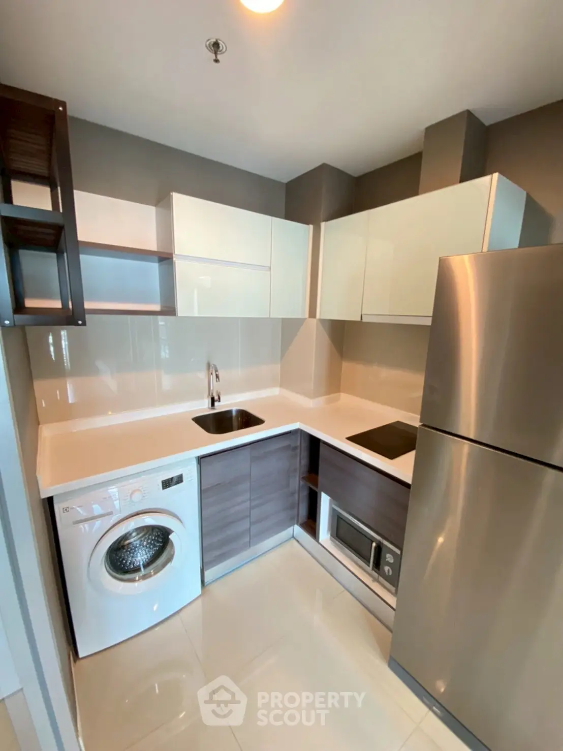 Modern kitchen with sleek cabinetry, washing machine, and stainless steel fridge.