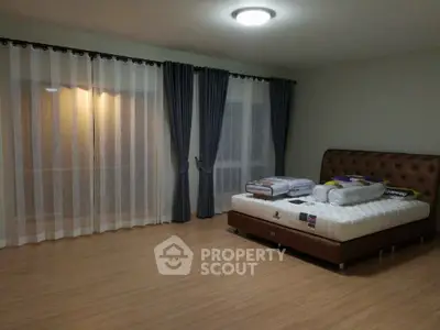 Spacious bedroom with elegant curtains and modern lighting, featuring a comfortable bed and wooden flooring.