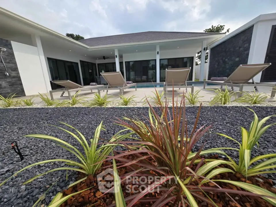 Luxurious modern villa with poolside loungers and landscaped garden