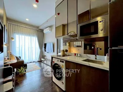 Modern open-layout kitchen with sleek appliances and cozy living area in a stylish apartment.