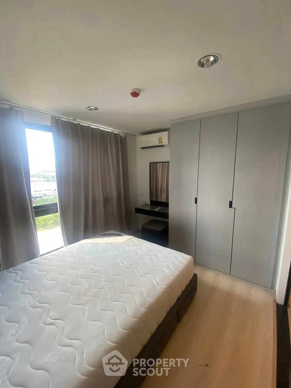 Modern bedroom with large window, built-in wardrobe, and sleek wooden flooring.