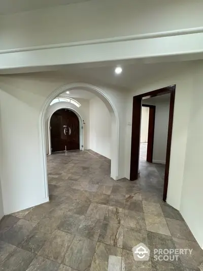 Elegant entrance with arched doorway and tiled flooring in a spacious home interior