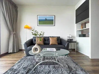 Modern living room with stylish decor, featuring a black leather sofa, glass coffee table, and elegant floor lamp.
