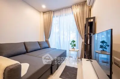 Modern living room with stylish gray sofa and large TV, featuring elegant curtains and bright lighting.