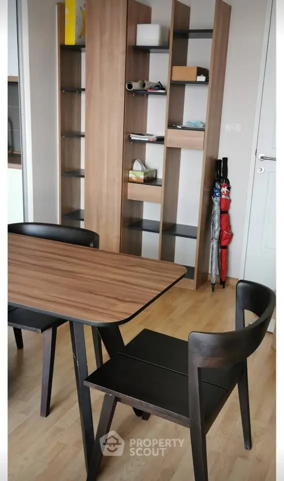 Modern dining area with wooden table and chairs, stylish shelving unit, and sleek flooring.