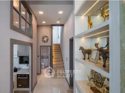 Elegant modern hallway with decorative shelves and staircase leading to upper floor.