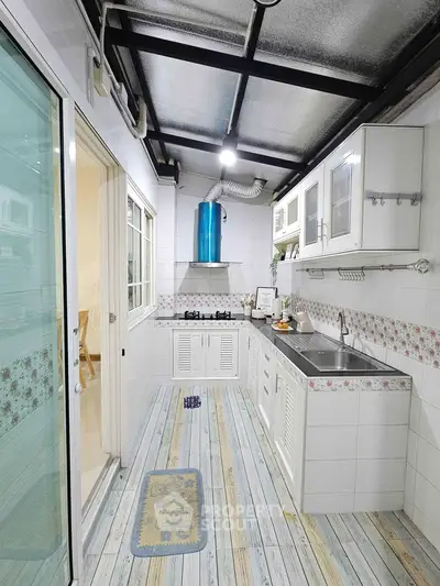 Charming kitchen with open layout and gas stove, featuring rustic flooring and modern cabinetry.