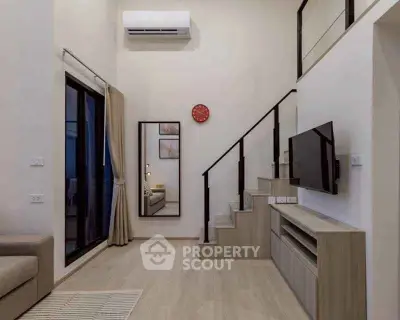 Modern living room with high ceiling, staircase, and wall-mounted TV in stylish apartment.