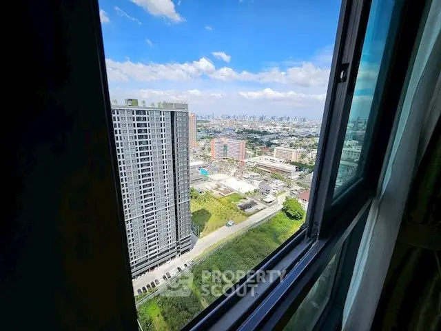 Stunning cityscape view from high-rise apartment window, showcasing urban skyline and blue skies.
