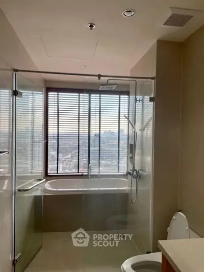 Luxurious bathroom with city view, featuring a glass shower and bathtub.
