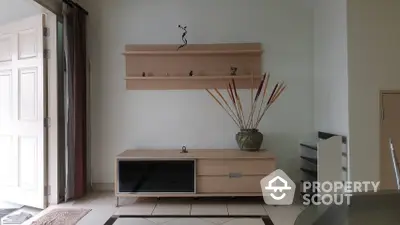 Spacious and well-lit living room with modern minimalist decor, featuring sleek TV stand and elegant shelving, perfect for urban living.